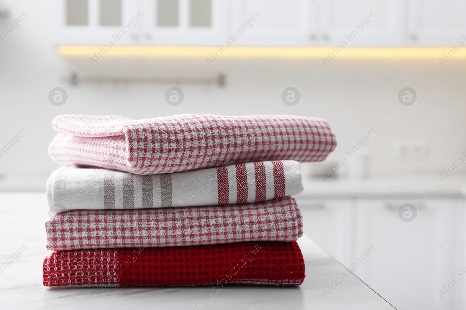 Photo of Stack of different clean towels on white table in kitchen