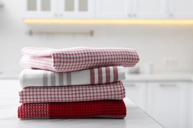 Photo of Stack of different clean towels on white table in kitchen