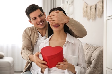 Man presenting gift to his beloved woman at home. Valentine's day celebration