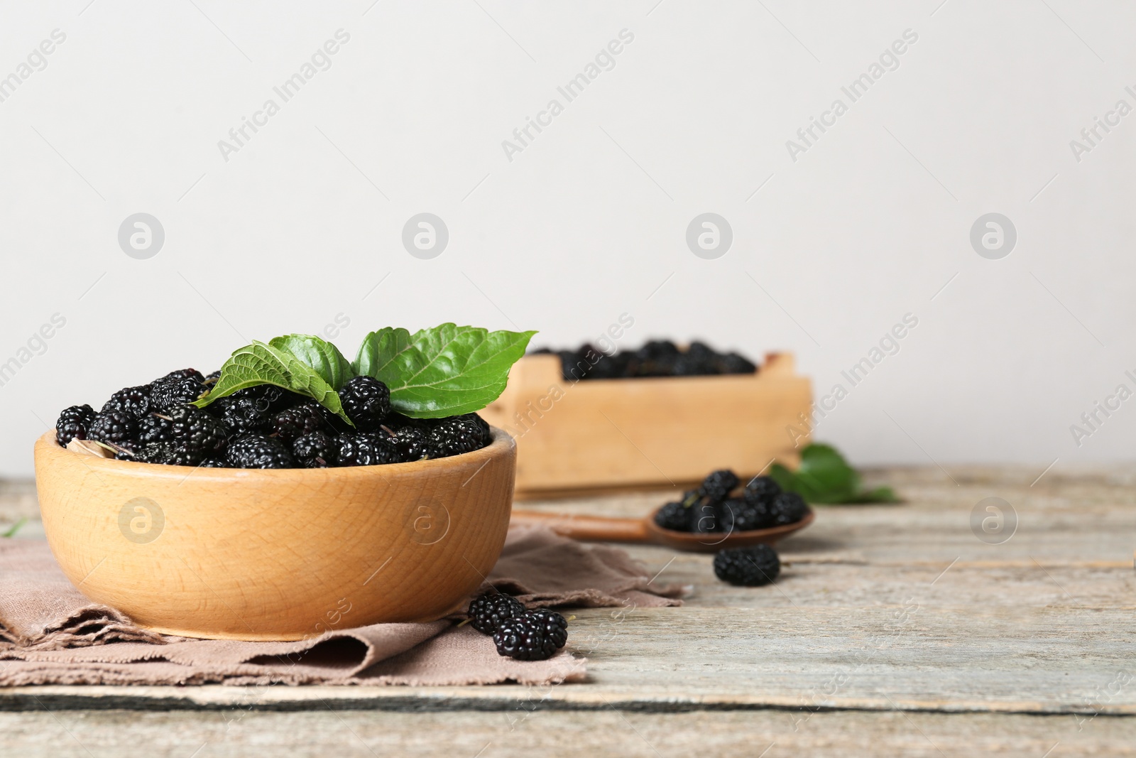 Photo of Bowl of delicious ripe black mulberries on wooden table. Space for text