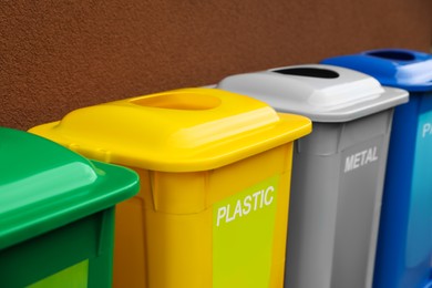 Photo of Many color recycling bins near brown wall, closeup