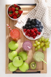 Photo of Glasses of different tasty smoothies and fresh ingredients on white wooden table, top view