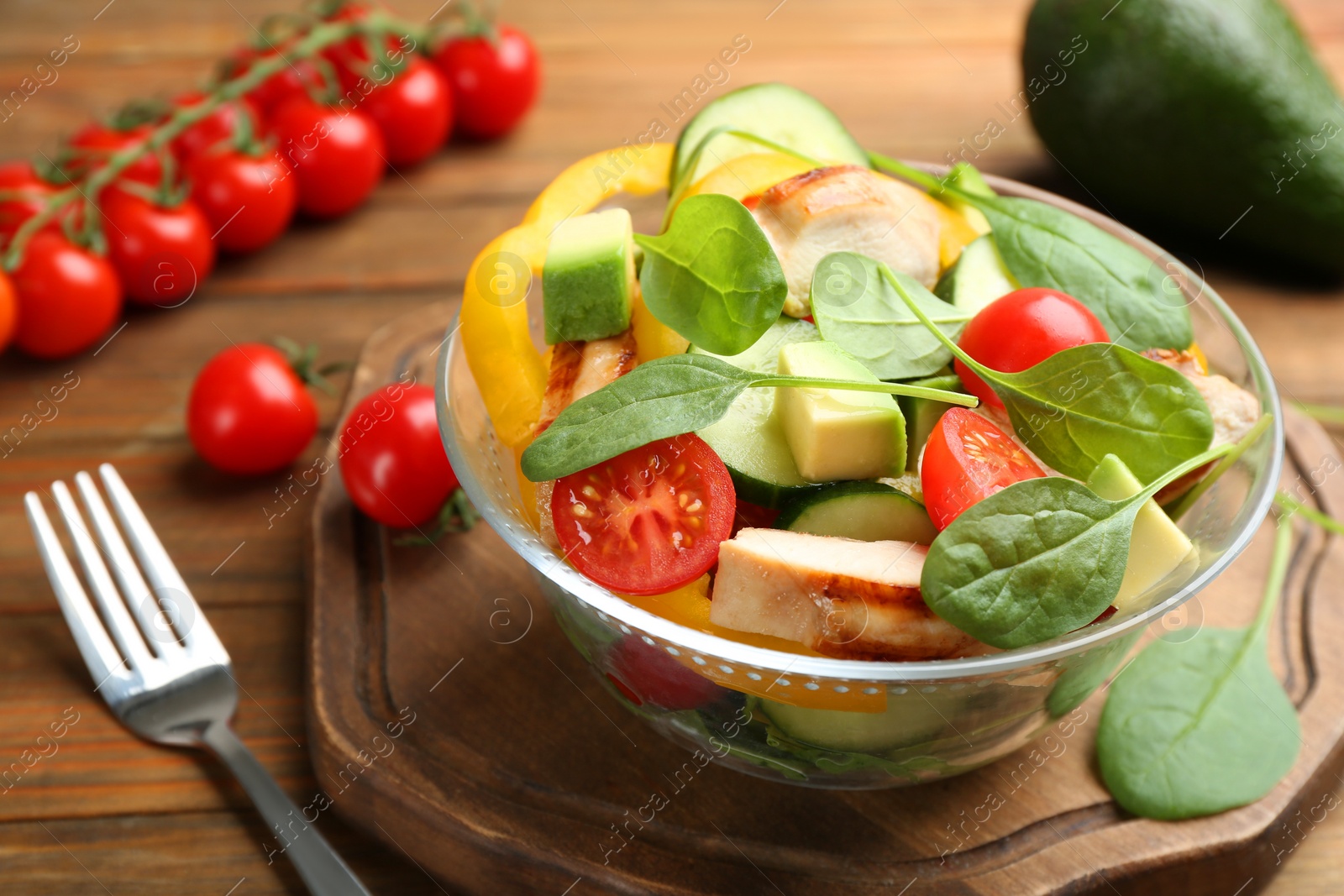 Photo of Delicious salad with chicken, vegetables and spinach on table, closeup