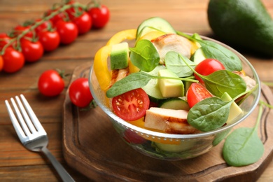 Delicious salad with chicken, vegetables and spinach on table, closeup