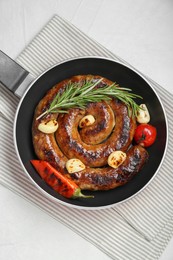 Photo of Delicious homemade sausage with garlic, tomato, rosemary and chili in frying pan on white table, top view
