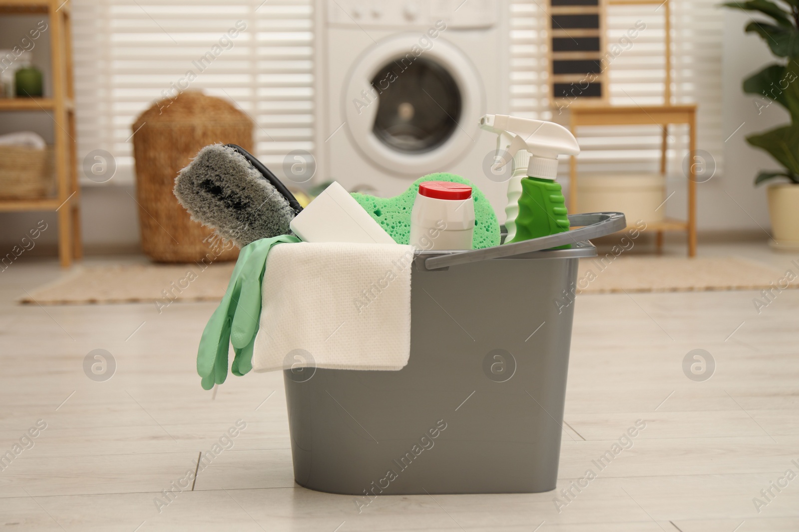 Photo of Different cleaning products in bucket on floor indoors