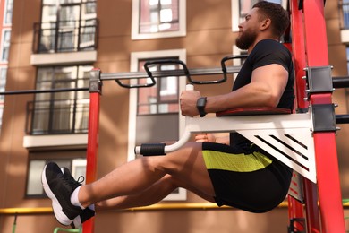 Photo of Man doing leg rise exercise at outdoor gym, low angle view