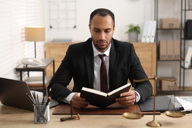 Serious lawyer reading book at table in office