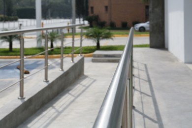 Photo of Concrete ramp with metal handrail near building outdoors, closeup
