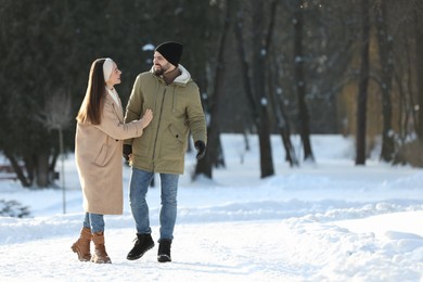 Photo of Happy young couple walking in snowy park on winter day