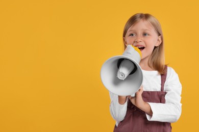Special promotion. Little girl shouting in megaphone on orange background. Space for text