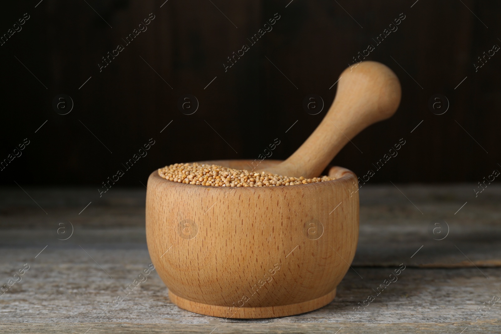 Photo of Mortar with mustard seeds on wooden table, closeup