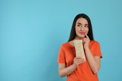 Dreamy young woman holding tasty shawarma on turquoise background. Space for text