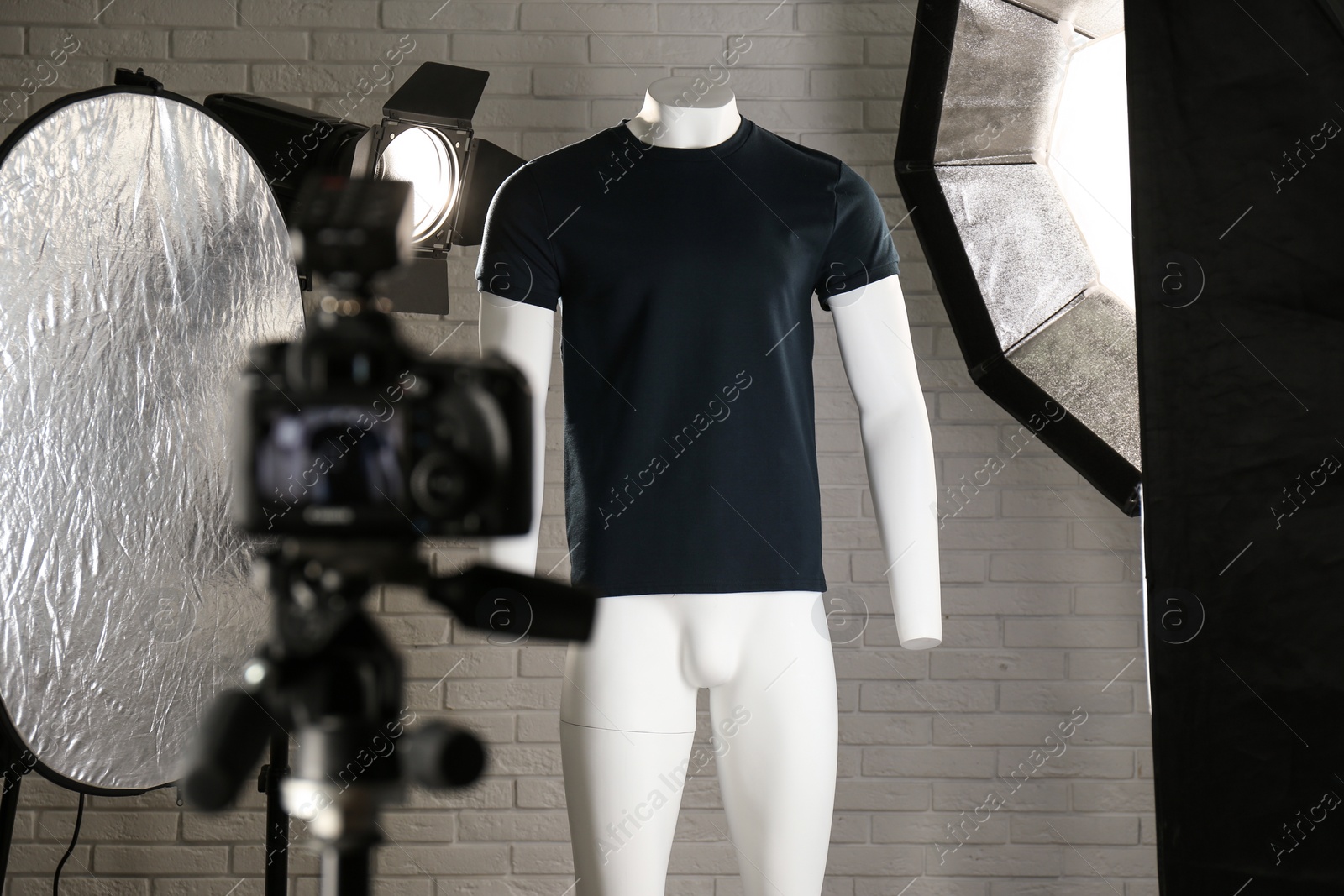 Photo of Stylish clothes on ghost mannequin and professional lighting equipment in modern studio. Fashion photography