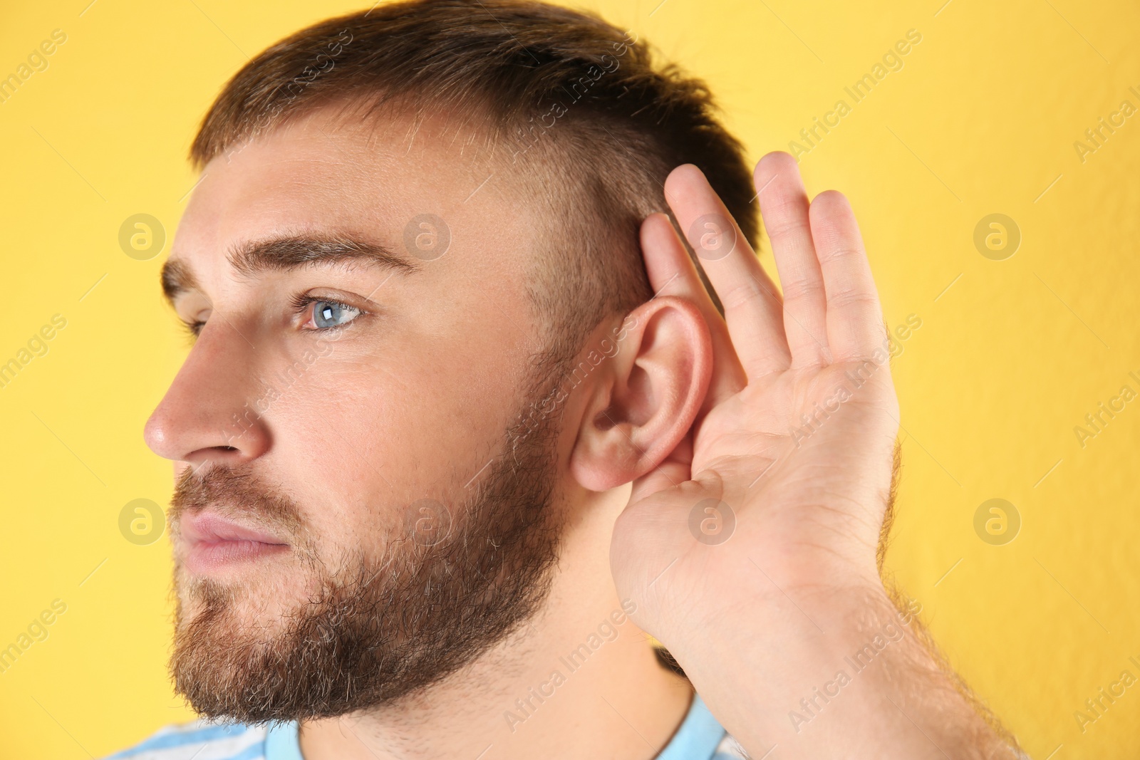 Photo of Young man with hearing problem on color background