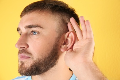 Photo of Young man with hearing problem on color background