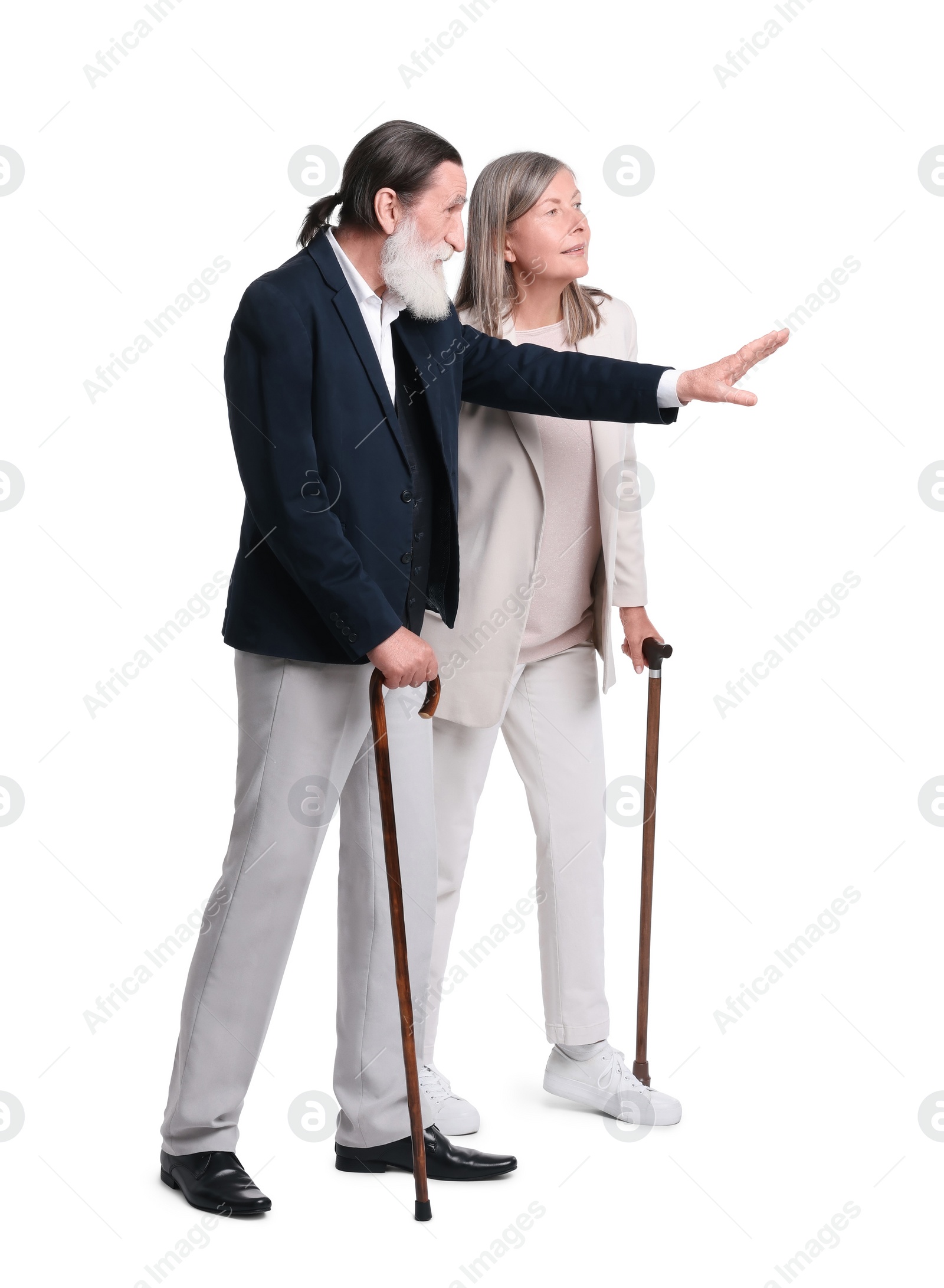 Photo of Senior man and woman with walking canes looking at something on white background