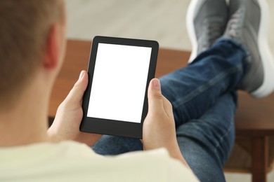 Man using e-book reader indoors, closeup view