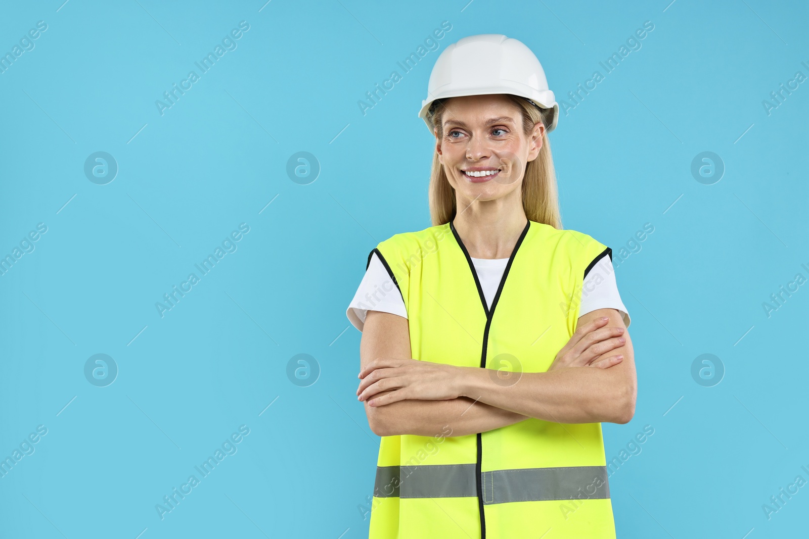 Photo of Engineer in hard hat on light blue background, space for text