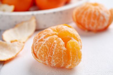 Peeled ripe tangerine on white table, closeup