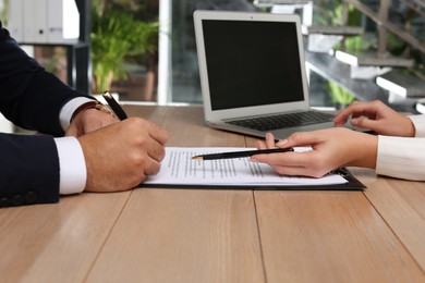 Photo of Businesspeople working with contract at wooden table indoors, closeup