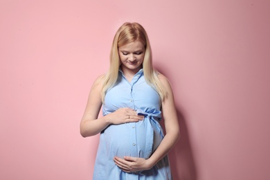 Beautiful pregnant woman in dress on color background