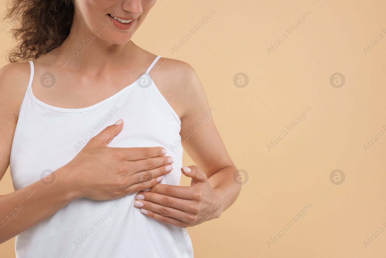 Photo of Woman doing breast self-examination on light brown background, closeup. Space for text