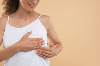 Woman doing breast self-examination on light brown background, closeup. Space for text