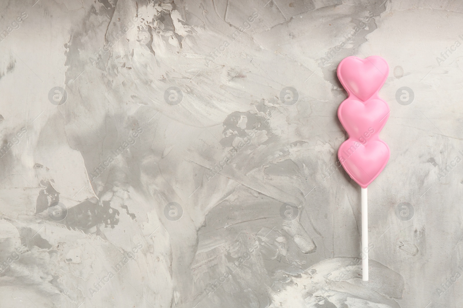 Photo of Chocolate heart shaped lollipop on table, top view. Space for text