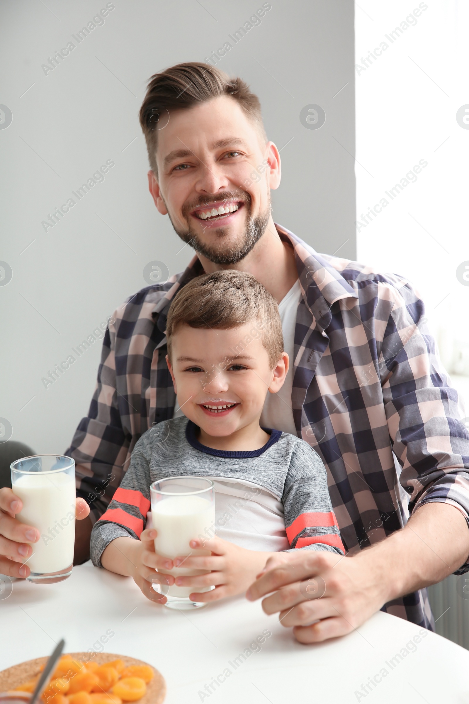 Photo of Father and son having breakfast with milk at table