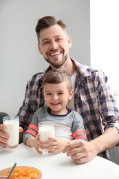 Father and son having breakfast with milk at table