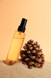 Bottle with serum and cone on sand against orange background. Cosmetic product