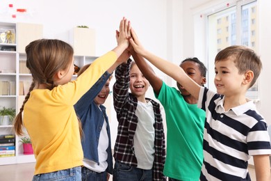 Happy children giving high five at school
