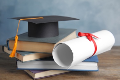 Photo of Graduation hat, books and student's diploma on wooden table