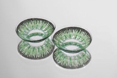 Photo of Two green contact lenses on mirror surface