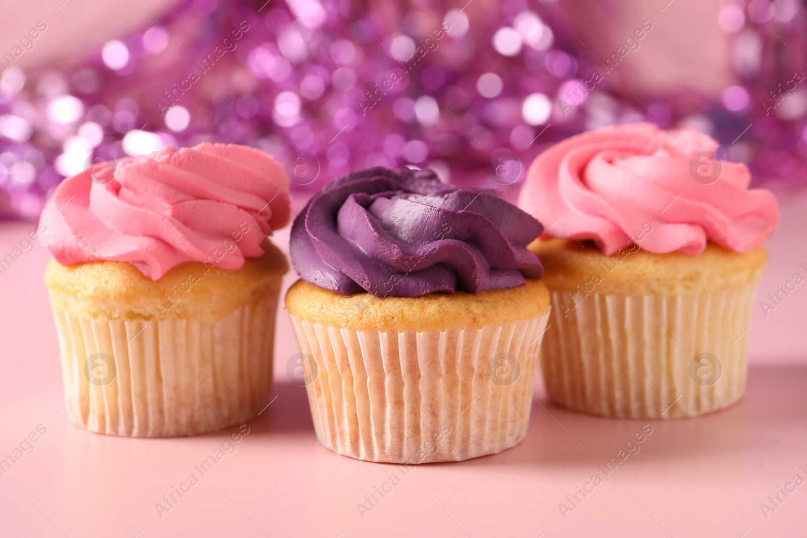 Photo of Delicious cupcakes with bright cream on pink background, closeup