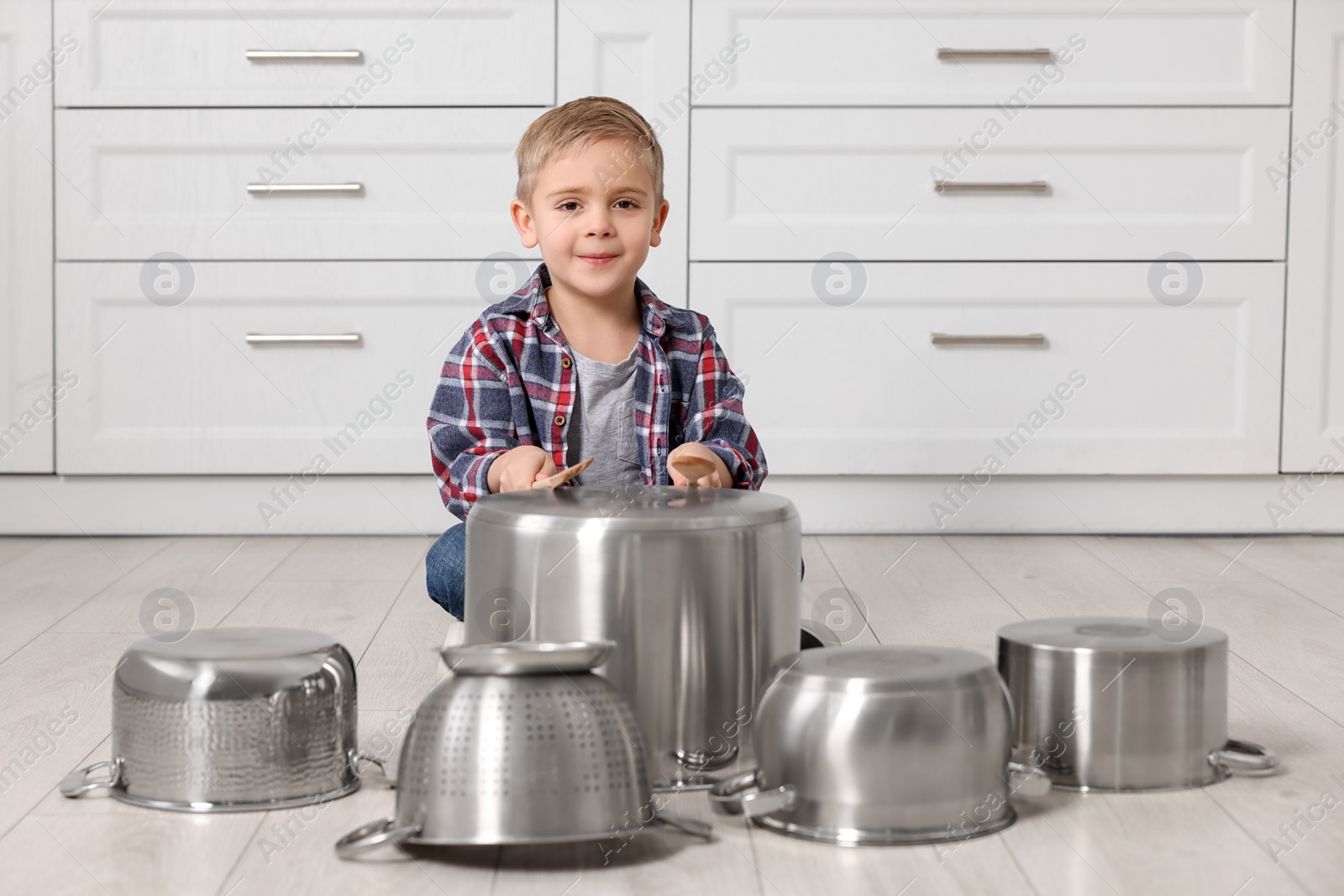 Photo of Little boy pretending to play drums on pots in kitchen