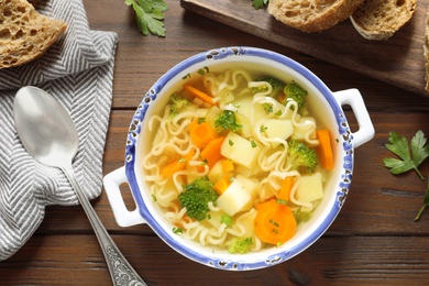 Photo of Dish of fresh homemade vegetable soup served on wooden table, flat lay