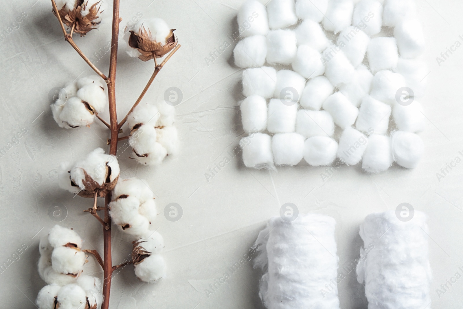 Photo of Flat lay composition with cotton balls, rolls and flowers on grey stone background