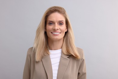 Portrait of smiling middle aged businesswoman on light grey background