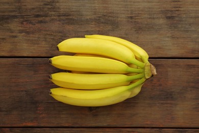 Photo of Bunch of ripe yellow bananas on wooden table, top view