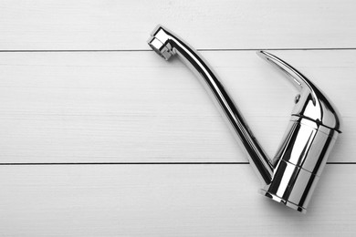 Photo of Single handle water tap on white wooden table, top view. Space for text