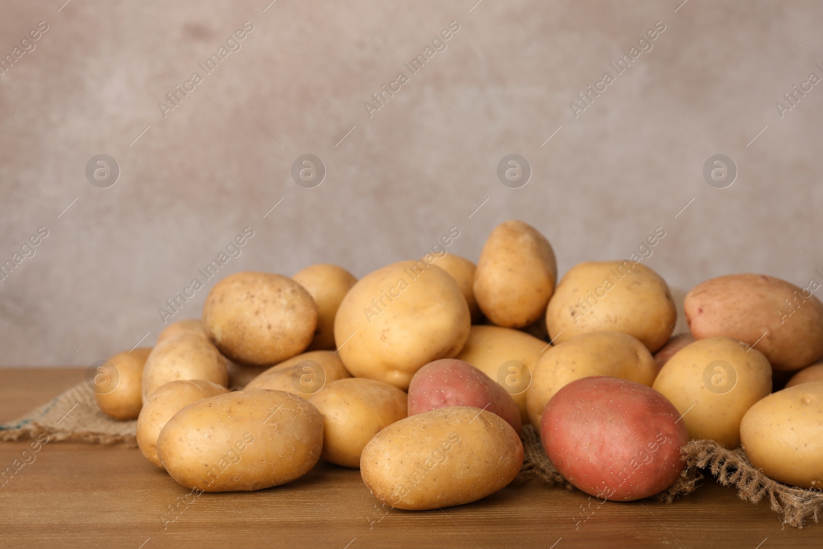 Photo of Pile of fresh organic potatoes on wooden table