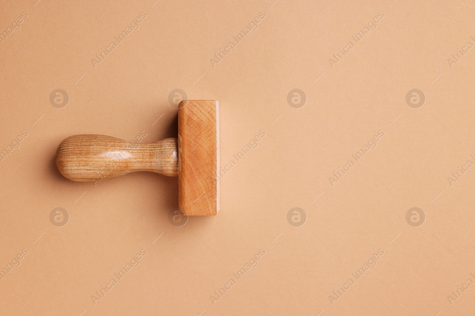 Photo of One wooden stamp tool on light brown background, top view. Space for text