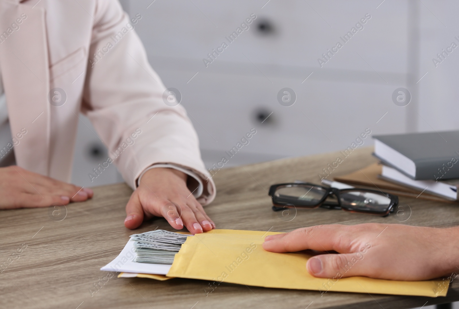 Photo of Man giving bribe to woman at table in office, closeup