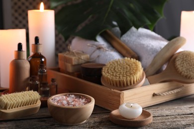 Composition with different spa products and burning candles on wooden table