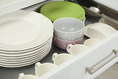 Photo of Clean plates, bowls, cups and butter dish in drawer indoors