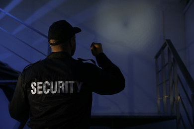 Photo of Male security guard with flashlight on stairs in darkness