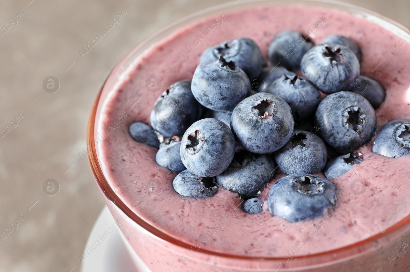 Photo of Glass with blueberry smoothie on grey background, closeup