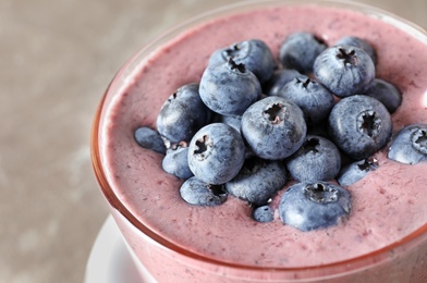 Glass with blueberry smoothie on grey background, closeup